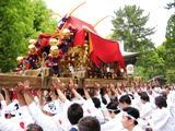 参道で渡御出立つを差し上げでご挨拶。
担ぎ棒短い末広は介添が担ぎ手の腰砕けを防ぐため必ず腰を押す。07.05.18.
